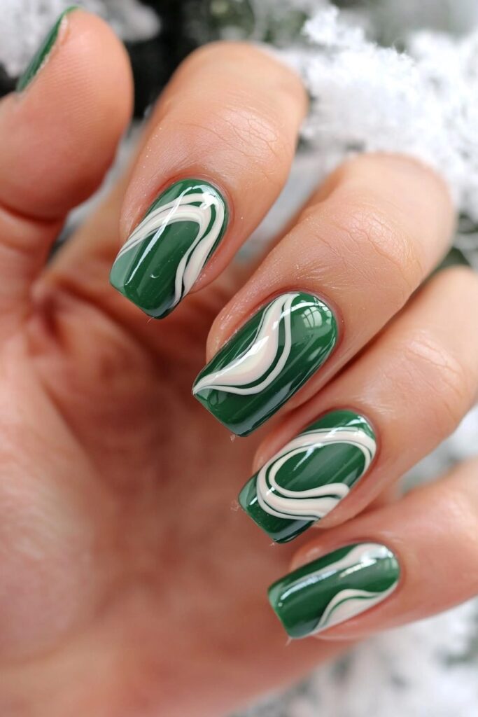 Emerald green Christmas nails with elegant white swirl patterns