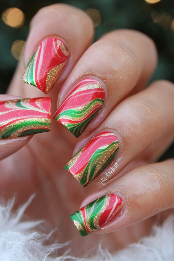 Red and green Christmas nail designs with swirling marble effect and gold accents.