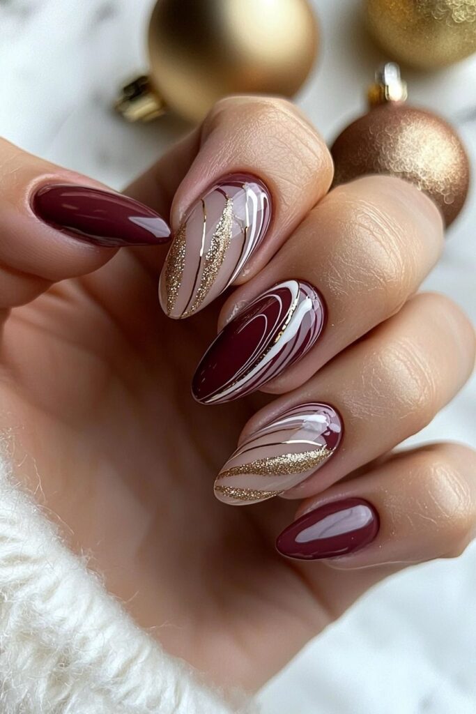 Christmas almond acrylic nails with burgundy and gold swirl patterns