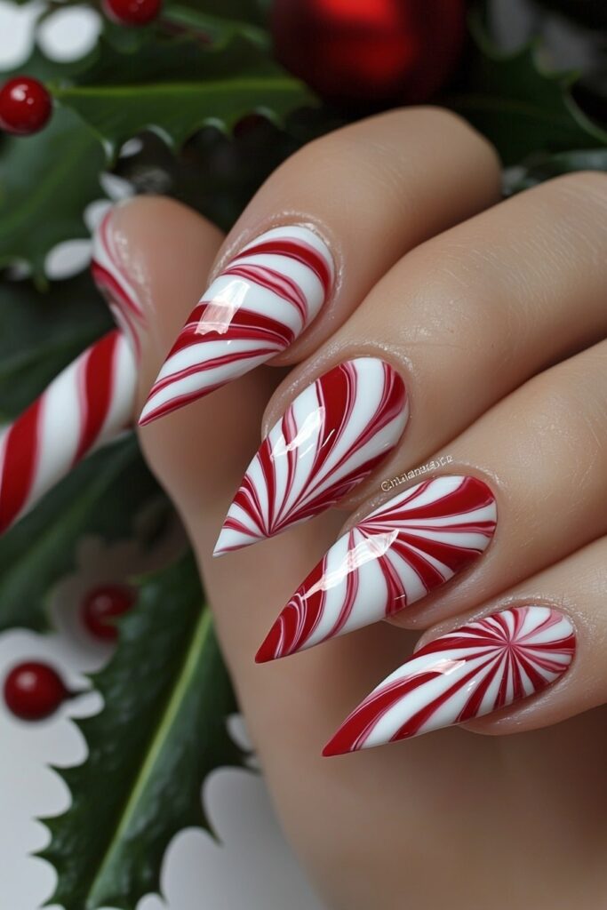 Christmas acrylic almond nails featuring red and white candy cane swirls