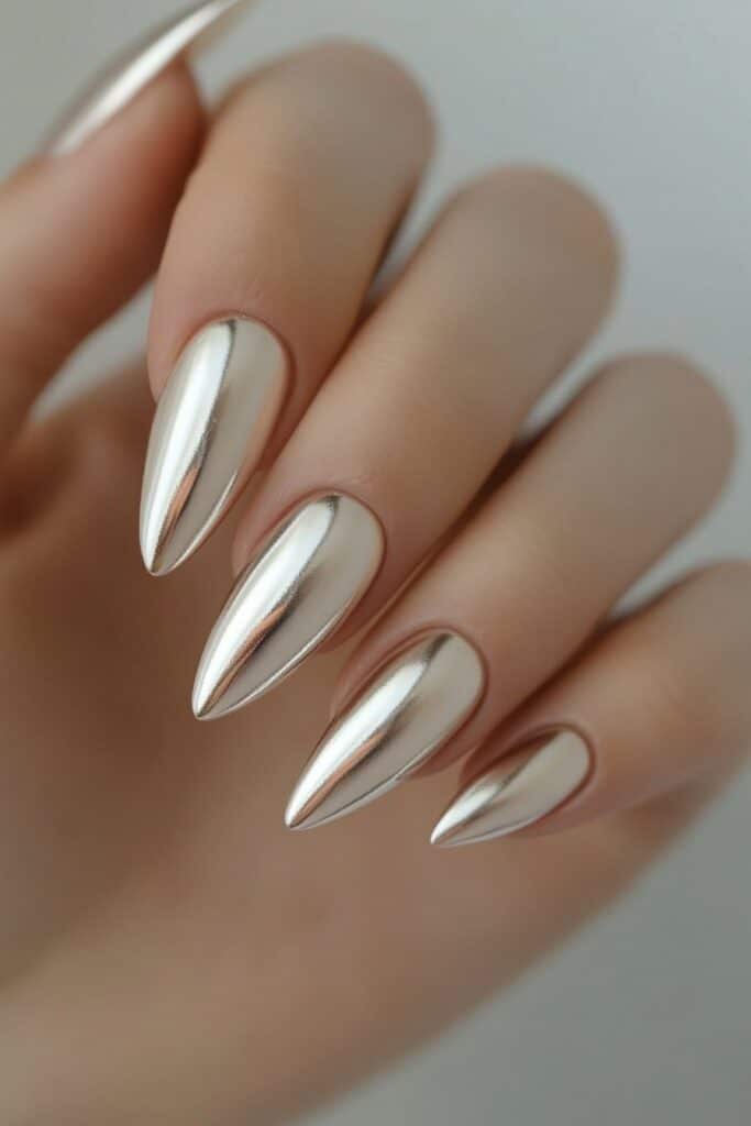 Sleek almond-shaped nails with a minimalist chrome finish, reflecting soft silver, pink, or gold hues for a clean, modern look.