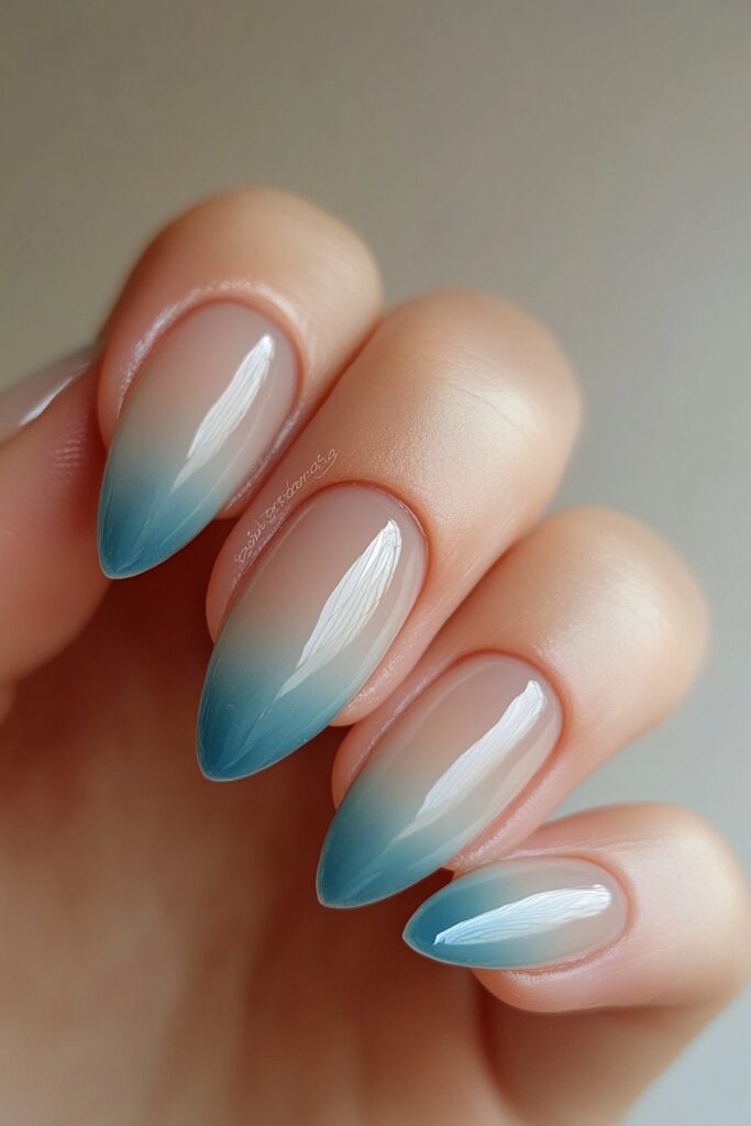 Almond-shaped nails with an ombre effect that transitions from deep ocean blue tips to soft seafoam green near the base, mimicking ocean waves.