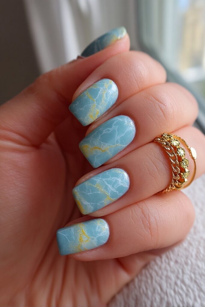 Luxurious summer nails with teal marble patterns veined with hints of white and gold, creating an elegant, sophisticated look with glossy finish.