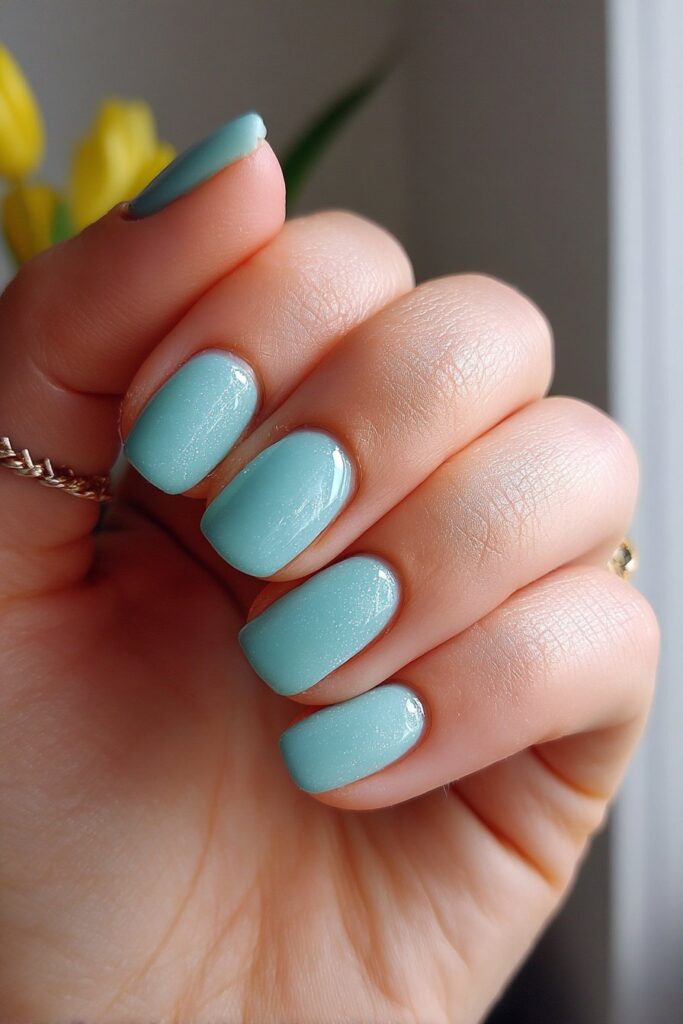 Short acrylic nails fully painted in a vibrant teal shade, offering a sweet and simple summer look with a glossy, healthy finish.