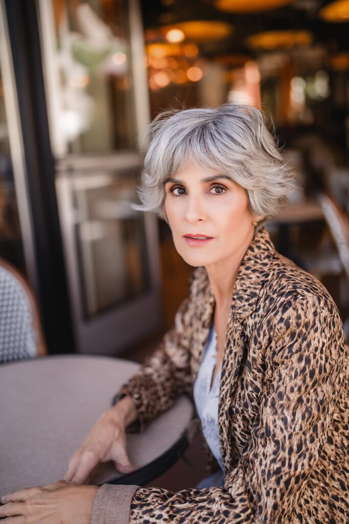 "Stylish café portrait of 50+ woman with balayage modern shag hairstyle in warm ambient lighting."