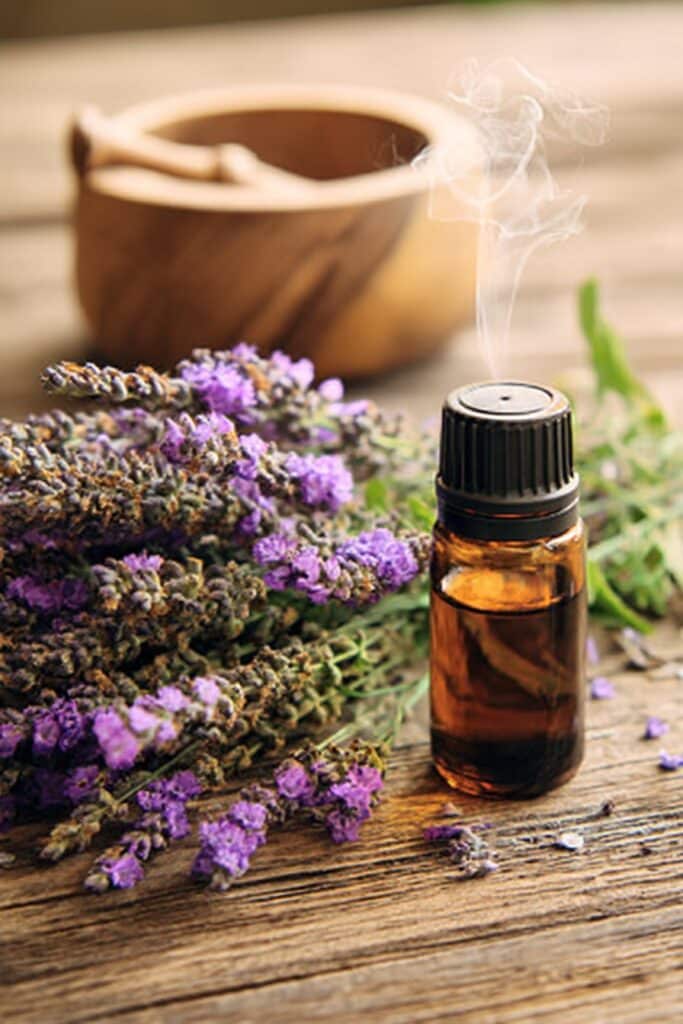 Lavender essential oil diffuser beside bed with relaxing vapor, creating soothing sleep environment.