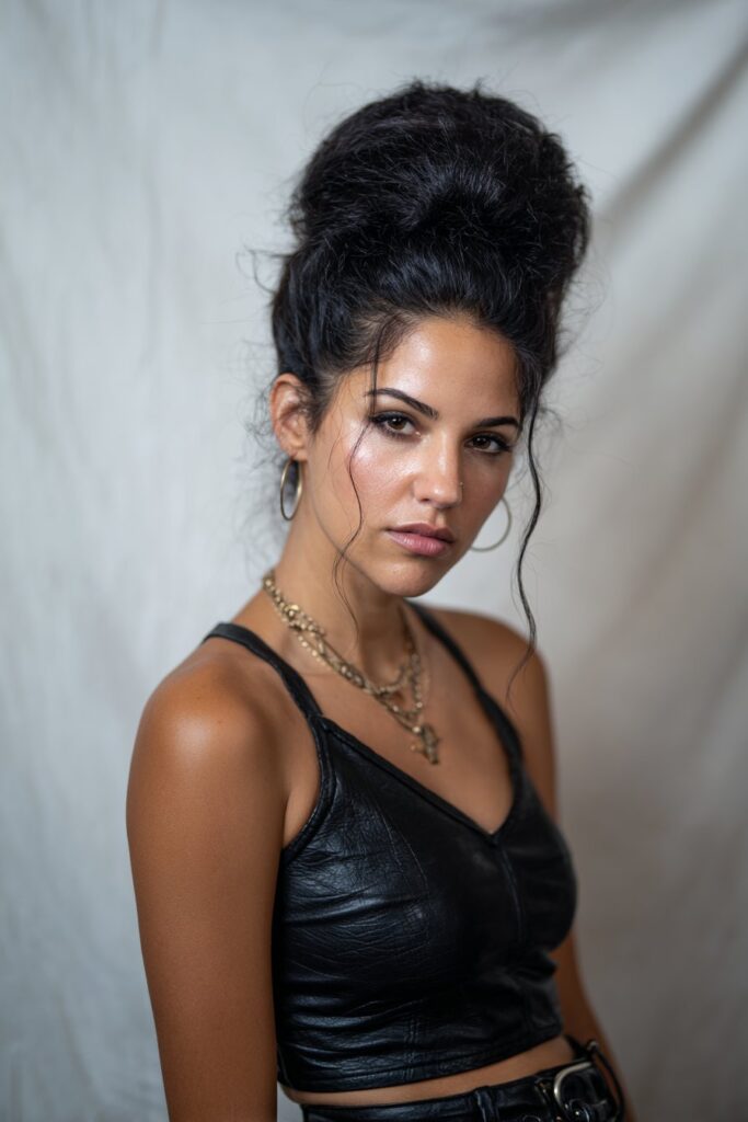 American woman with dramatic Amy Winehouse-inspired beehive hairstyle, retro eyeliner and statement rocker outfit against white background.