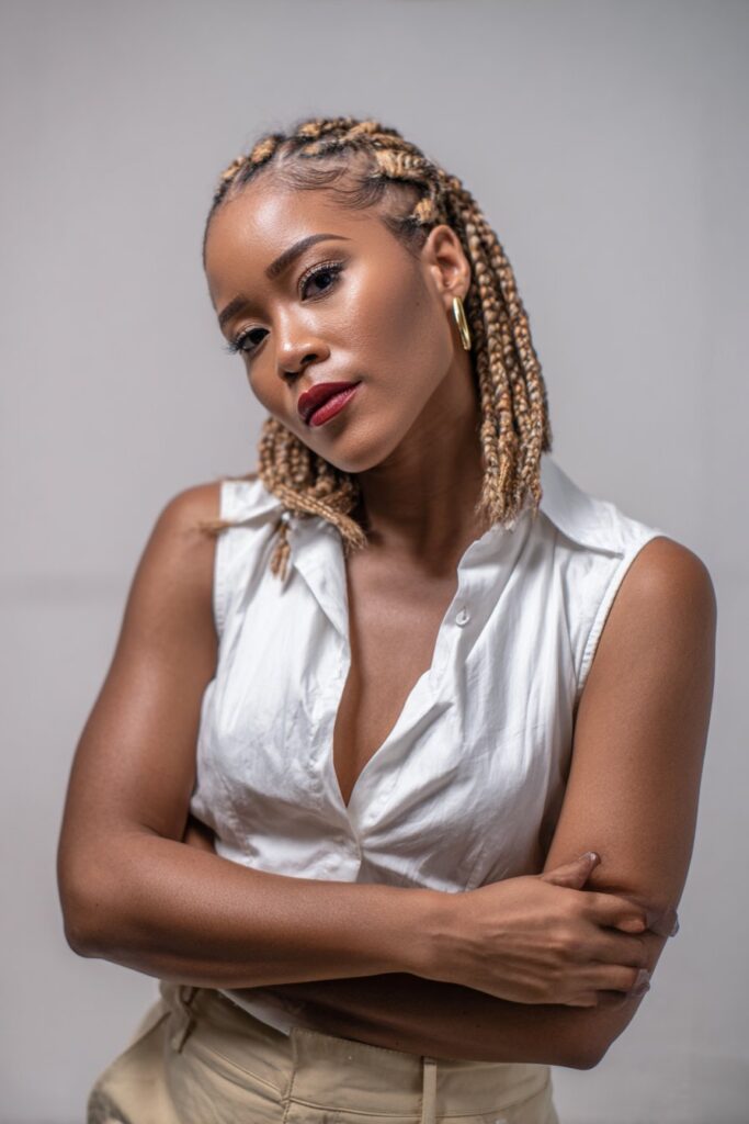 Studio portrait of American model with sleek chin-length braided bob and bold lipstick against white seamless background.