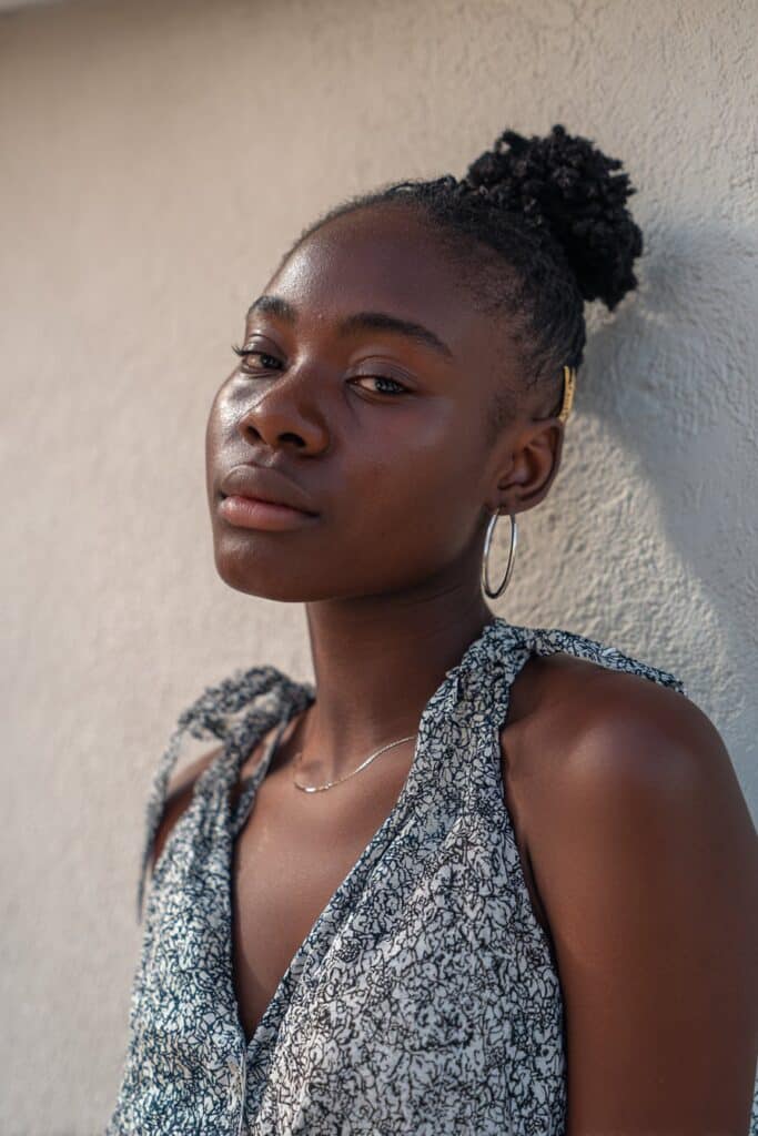 Minimal portrait of Black woman with short 4c hair in claw clip updo, soft volume against plaster backdrop.