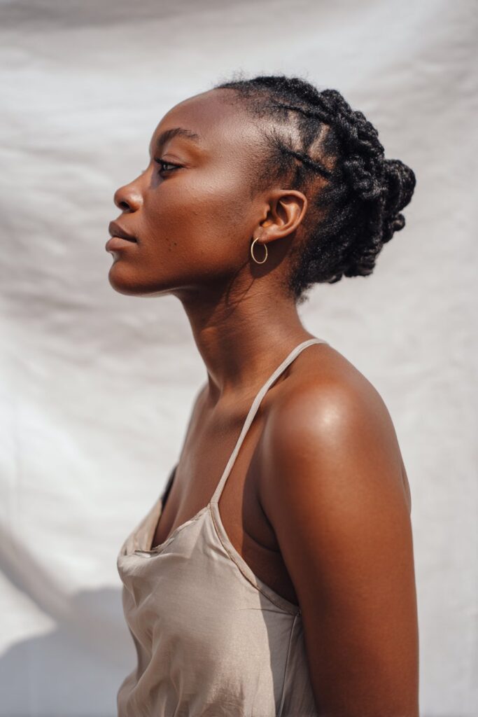 Elegant portrait of Black American woman with short 4c hair in sleek flat twists, minimalist beauty against white backdrop.
