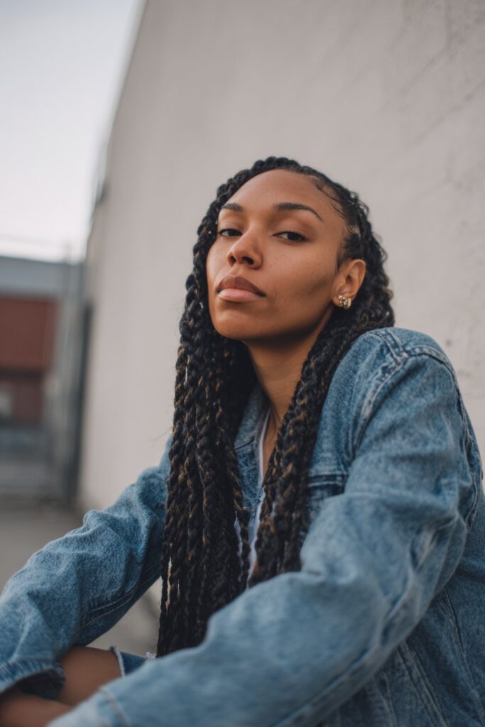 Portrait of American model with waist-length glossy box braids in Jayda Wayda style against clean white studio background.