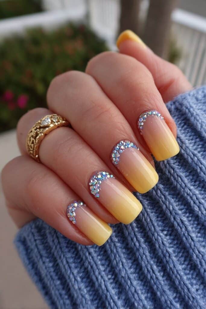 Orange ombré French tips decorated with tiny crystal gems for festive elegant summer nail art with sparkling accents.