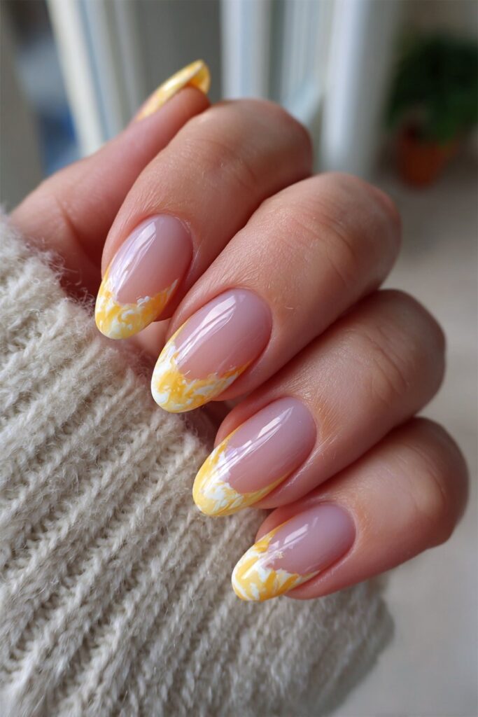 Almond-shaped nails featuring clear bases and vibrant orange swirl French tips creating stylish and summery manicure design.