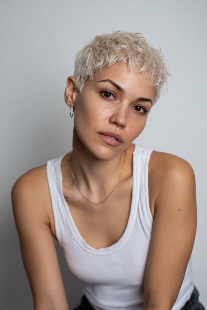 American model with messy crown volume pixie, soft chocolate tone, shimmer makeup, cozy top in natural forest.