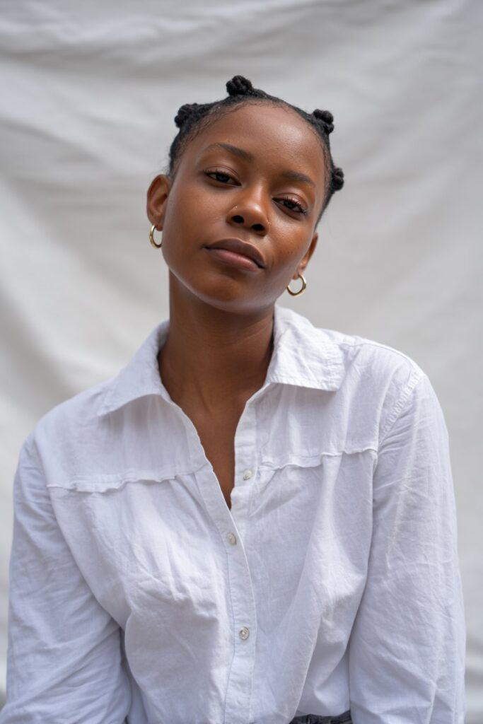 Simple portrait of Black American woman with short 4c hair in protective two-strand twists against white backdrop.