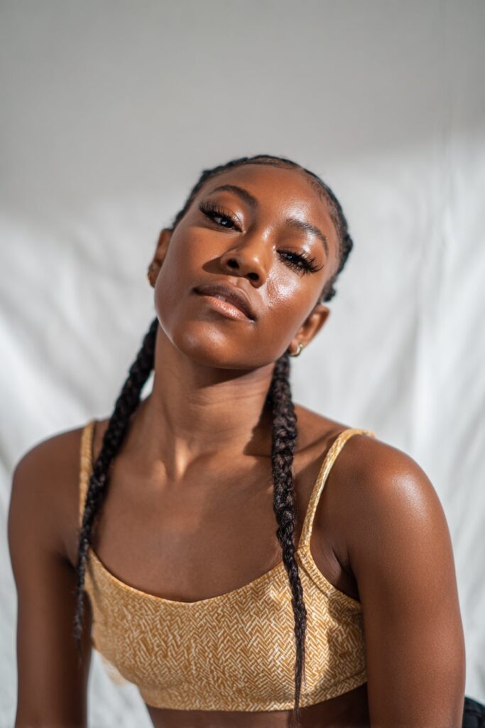 African-American woman wearing two sleek, symmetrical Jayda Wayda-style braids with center parting and laid baby hairs.