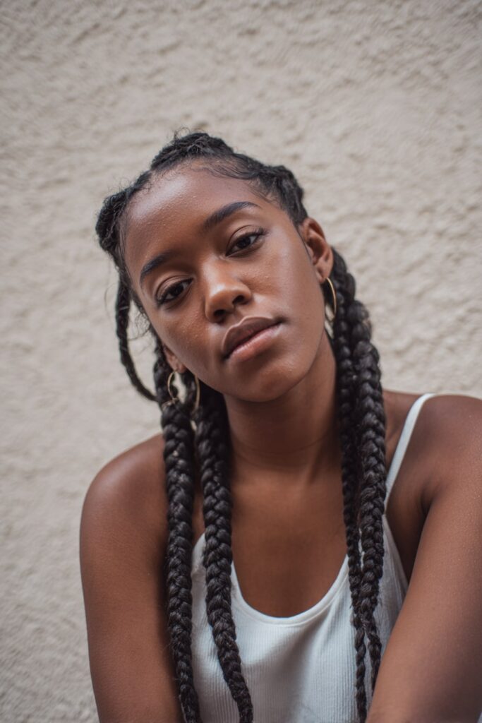Model with four neatly sectioned Jayda Wayda braids, clean partings and long, smooth braids hanging down.