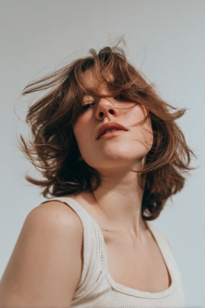 Woman with short feathered layers sitting just above the shoulders, soft flips at the ends and light body throughout, styled simply in front of a seamless white studio backdrop.