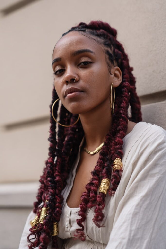 Jayda Wayda-style Fulani braids made with deep red braiding hair, long length, gold cuffs, and curly finish.