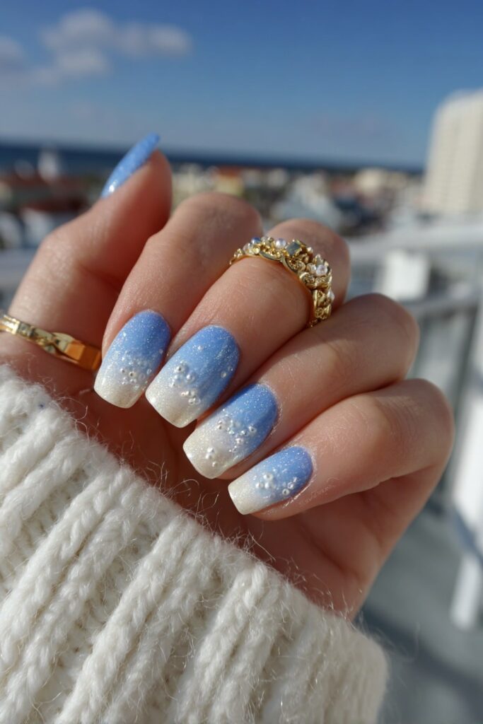 Elegant nails in pastel blue and white gradient featuring miniature pearl embellishments.