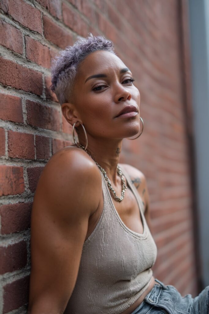 Jayda Wayda-style pixie cut with bold color streaks—caramel, red, and honey blonde—worn by a glam Black model in a brick wall setting.