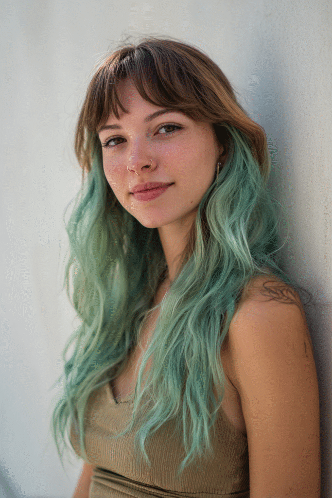 A vibrant American female model in her 20s with chest-length Neapolitan hair featuring vibrant mint green with rich cocoa hues, styled smoothly, photographed against a seamless white backdrop with minimal texture. She wears subtle makeup, a trendy outfit, and has a warm skin tone with a friendly expression, captured with soft natural lighting.