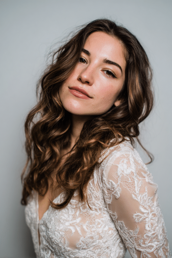 A gorgeous young Black American bride with glamorous Hollywood waves and a deep side part in a rich mocha shade, wearing an elegant full-length winter wedding dress with velvet long sleeves, radiant expression, warm skin tone, against a seamless soft linen backdrop with a matte finish, icy blue winter undertones.
