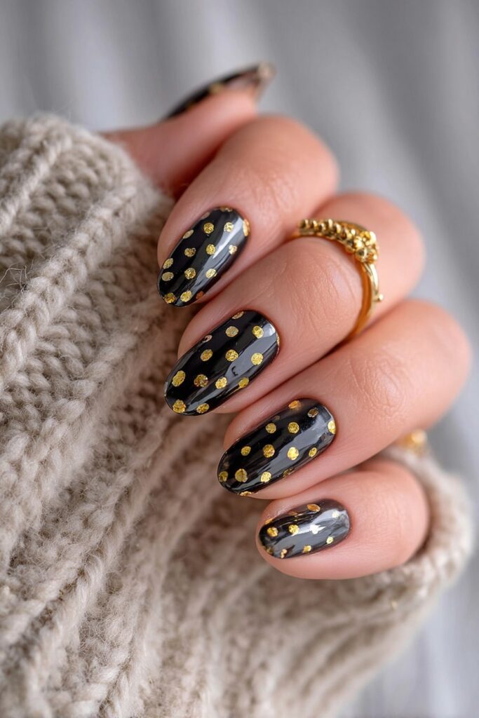 Luxurious black polka dot nails accented with shimmering gold foil for a glam look.