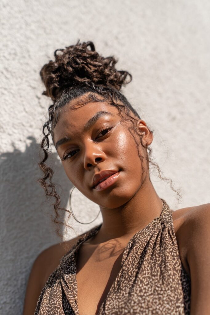 Black girl with half-up bohemian knots, braiding hair, dark brown, white backdrop.