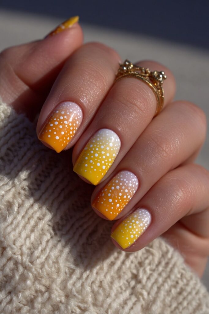 Halloween nails inspired by candy corn gradient with yellow, orange, and white polka dots.