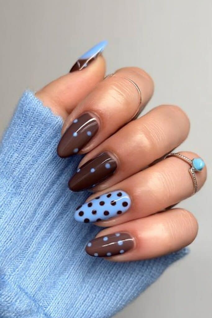 Trendy mix of chocolate brown and baby blue polka dot nails, alternating colors for a playful yet elegant finish, photographed in bright natural light.