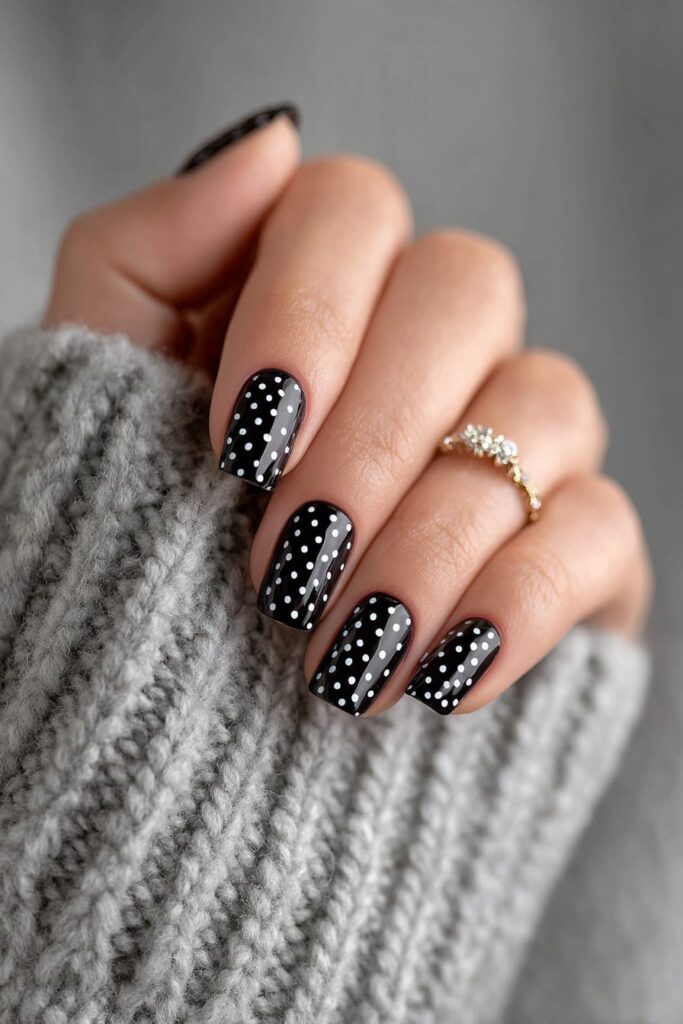 Elegant black and white polka dot nails with glossy finish and perfect symmetry.