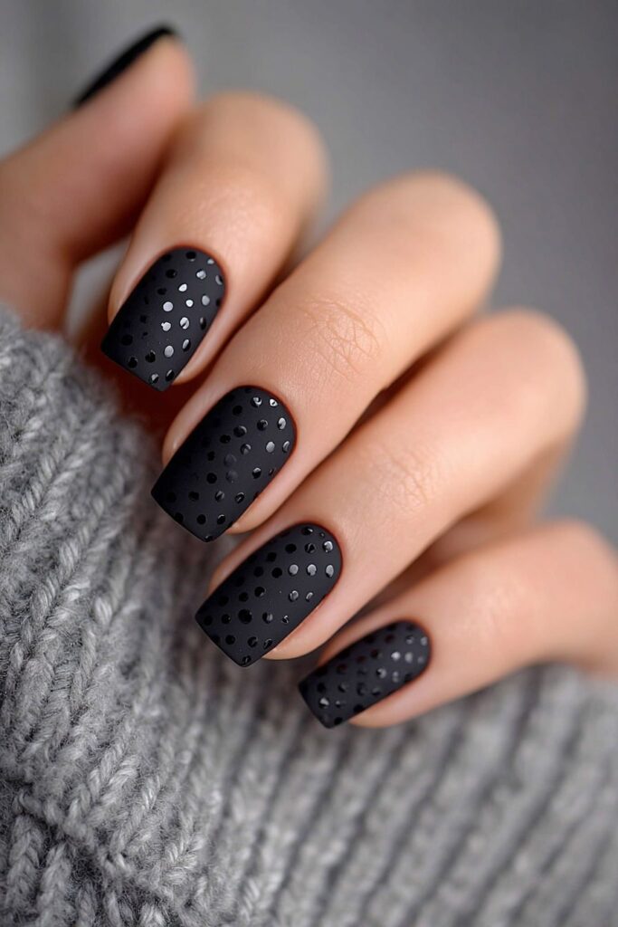 Trendy matte black nails featuring glossy black dots for a chic textured look.