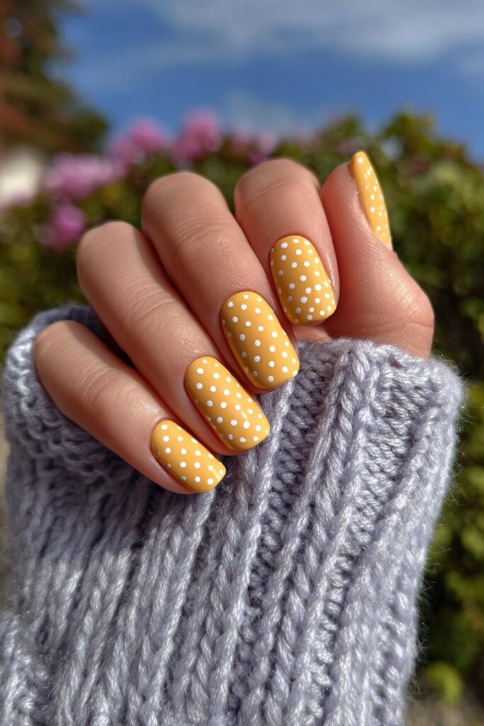 Minimalist butter yellow nails with delicate white polka dots for a fresh, modern look.