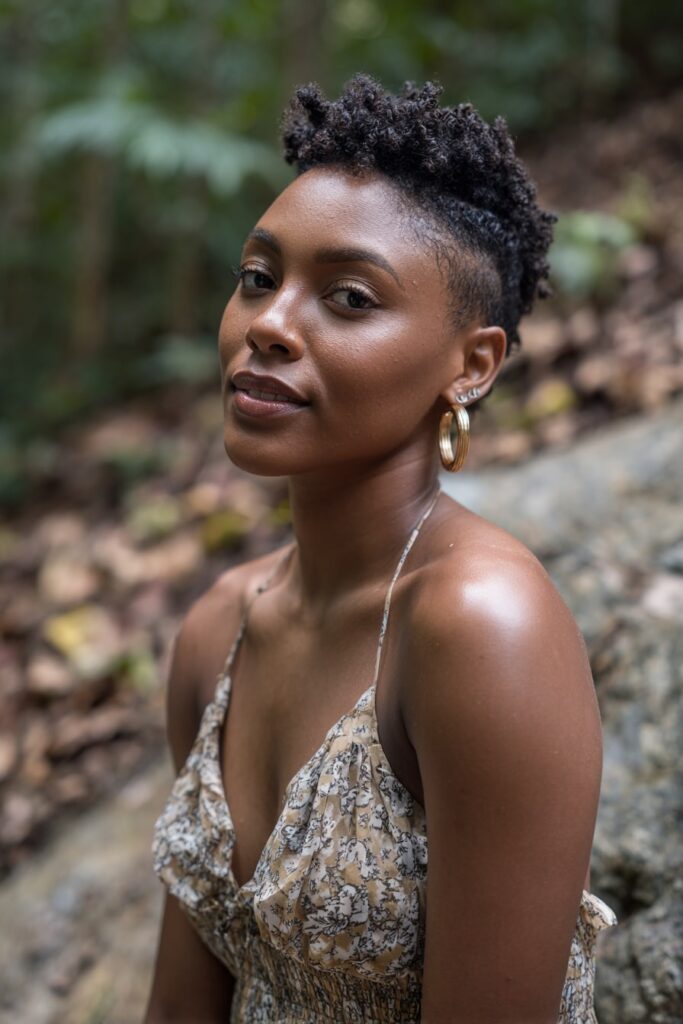 Woman with short 3c curly shag, natural black hair, natural forest backdrop.