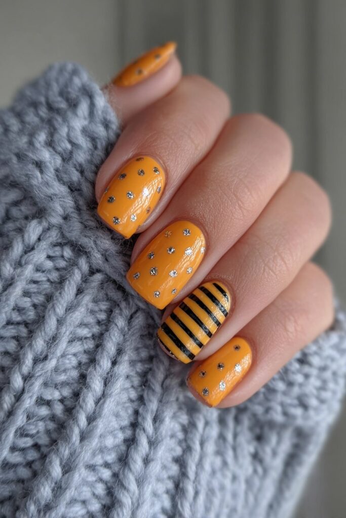 Halloween nail art with orange stripes and black polka dots for bold spooky style.