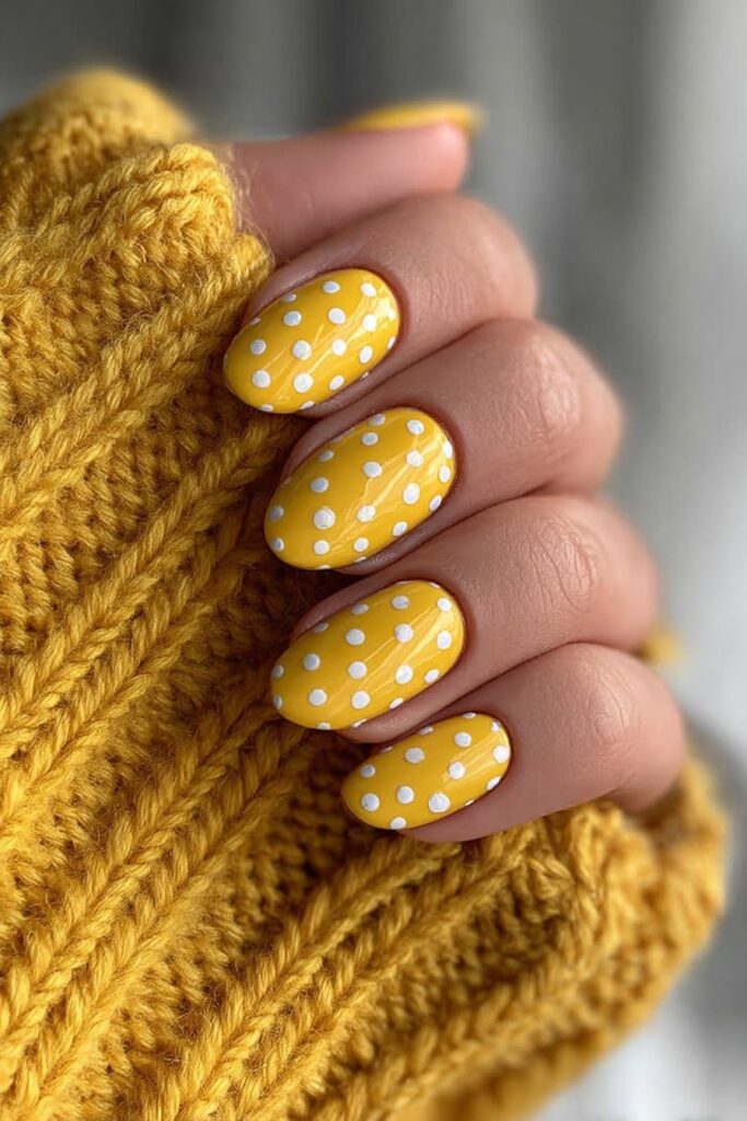 Matte yellow nails contrasted with glossy polka dots for a chic and textured manicure.