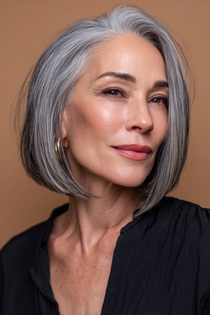An American woman over 60 with a sleek blunt lob styled with a side part, straight and glossy hair accentuating her features, captured against a bronze satin background.