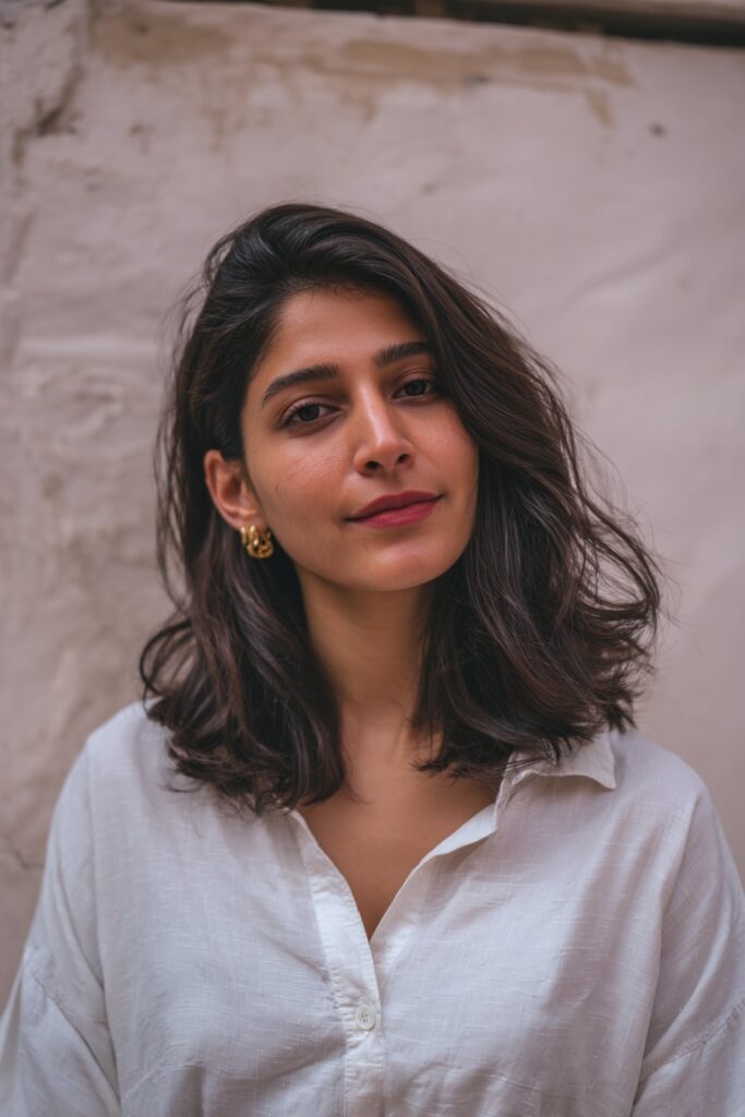 A radiant American woman in her 20s with medium-length hair styled in soft face-framing layers, enhancing her natural features, posed against a silky soft mint backdrop.