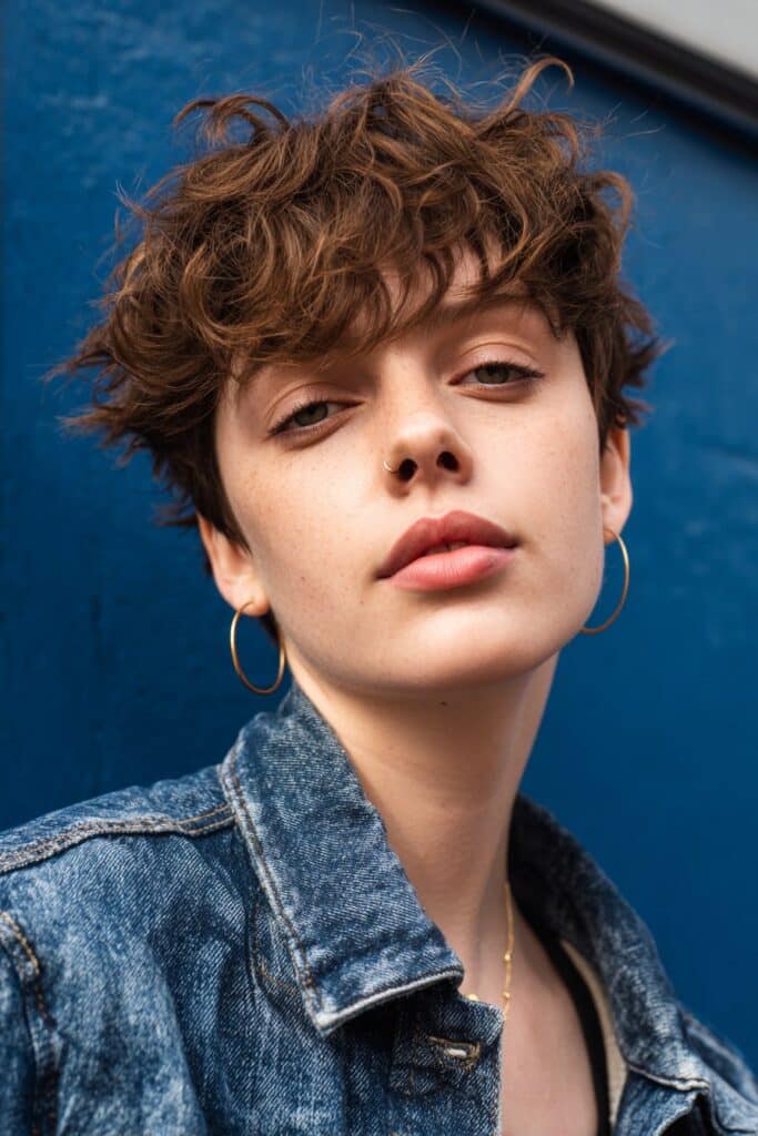 A hybrid shaggy pixie mullet haircut with short textured pieces on the sides and a slightly elongated, choppy back section. The cut combines pixie edginess with mullet softness, creating a bold, modern short hairstyle.