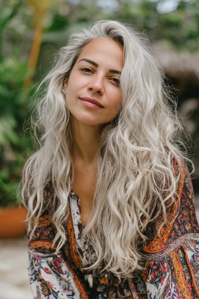 Woman in her 20s wearing boho-inspired platinum layers, soft flowing icy blonde hair captured in a garden background.