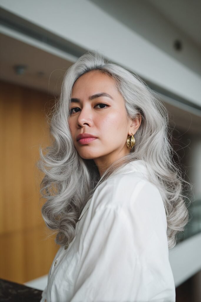 Woman in her 20s with classic platinum blonde waves, flowing icy curls photographed on a historic boutique hotel staircase.