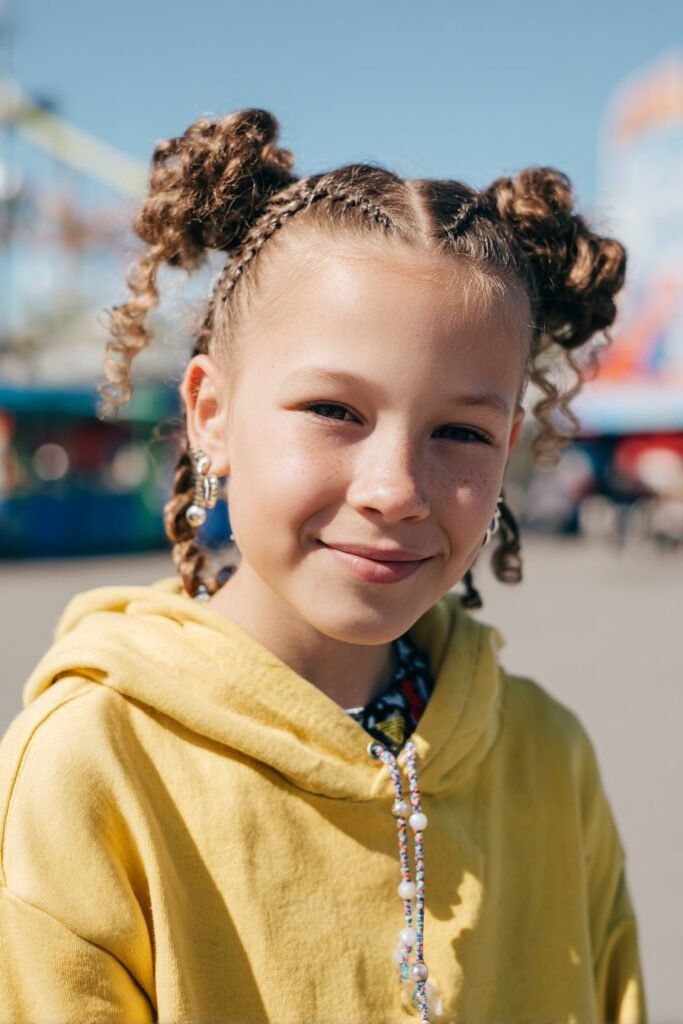 Double bun braids with beads on an 8-year-old girl, playground swing background, bright natural lighting, fun and energetic childhood vibe