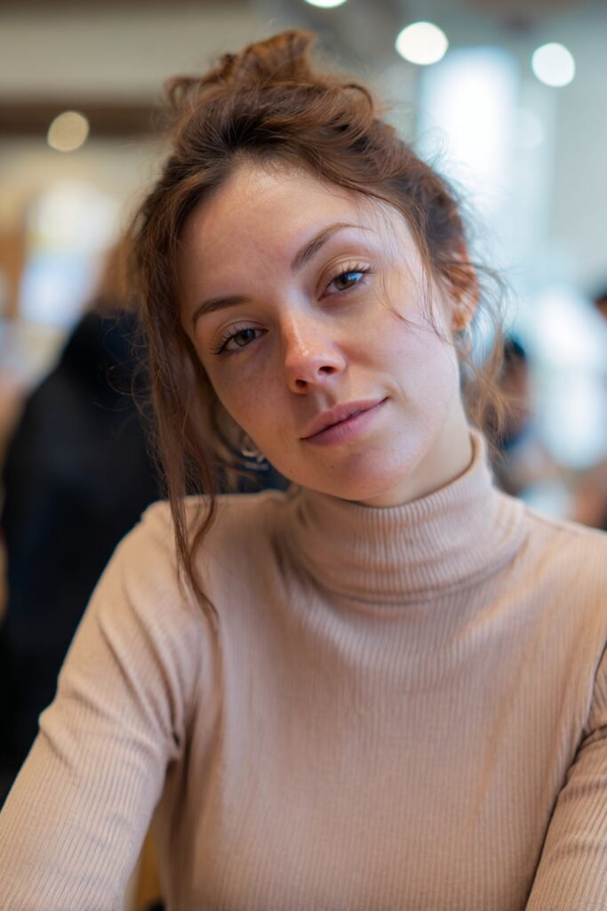 Woman in her 20s wearing a soft turtleneck styled with a mini claw clip updo inside a trendy coffee shop.