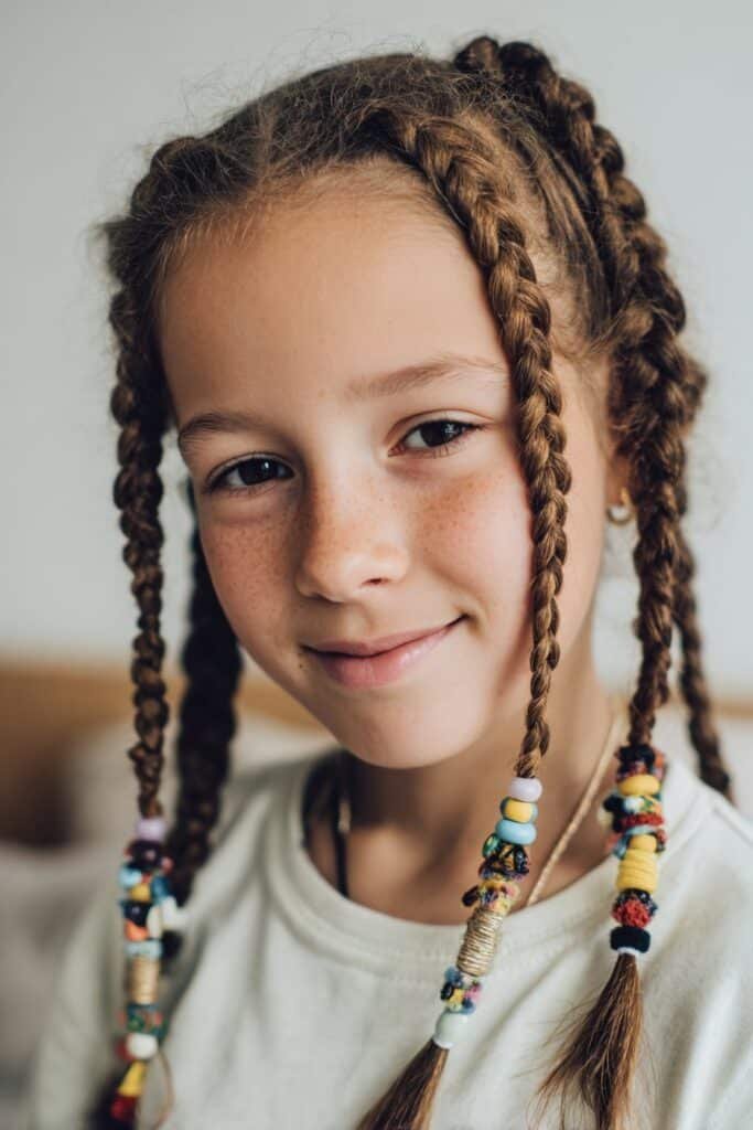 Protective braids with beads on a toddler, home living room background, natural window light, soft and calm mood