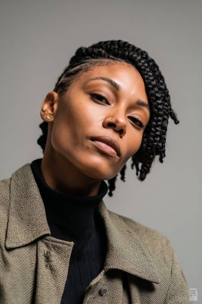 Chic woman wearing a structured turtleneck with short Fulani braids styled into a neat bob cut in a modern fashion studio.