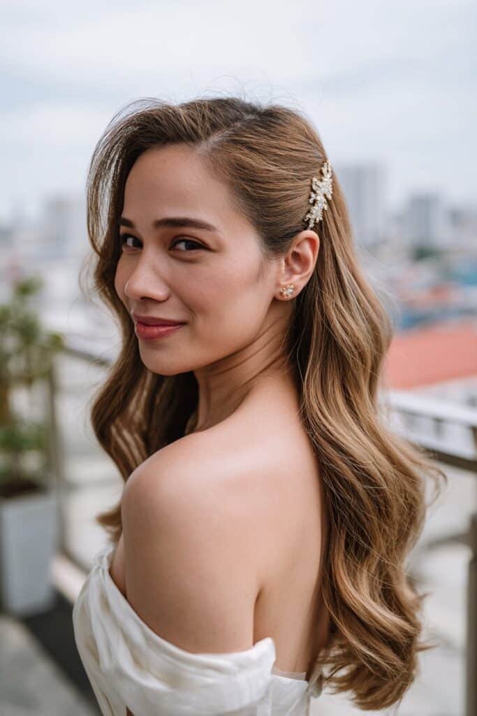 Bride in her 20s wearing side-swept waves wedding hairstyle pinned with a sparkly barrette at an elegant rooftop wedding venue.