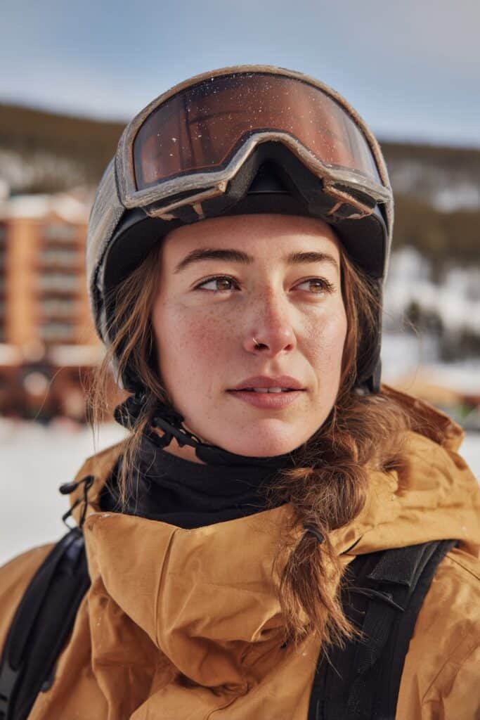 Front-view image of a woman in her 20s wearing a ski helmet with a messy fishtail braid, a relaxed ski hairstyle with visible texture.