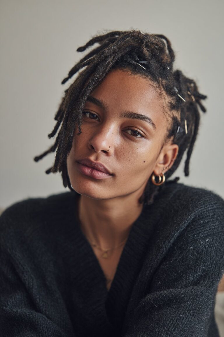 woman with short locs pinned back for open face look