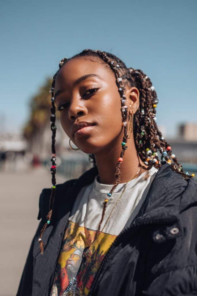 Black woman with braided twists decorated with small beads.